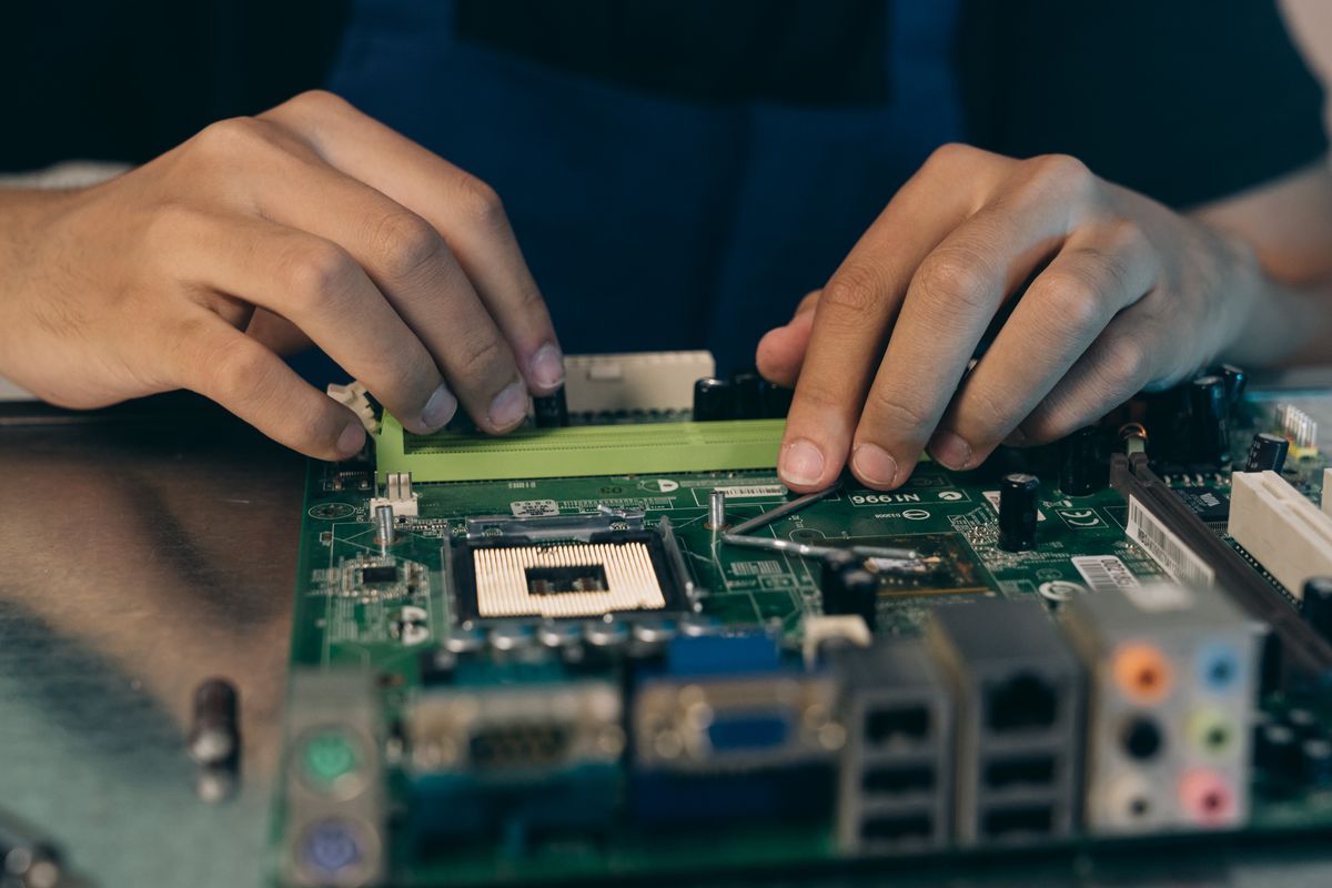 Hands assembling components on an electronic board